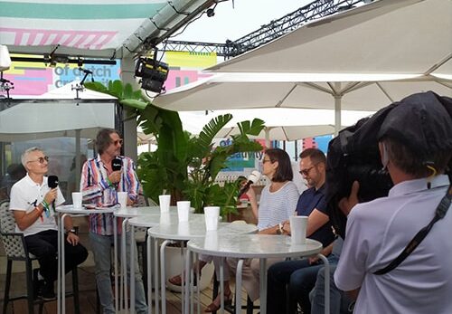 Cinq personnes discutent sous des parasols à Cannes.