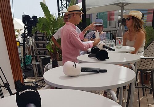 Trois personnes discutent autour de tables hautes.