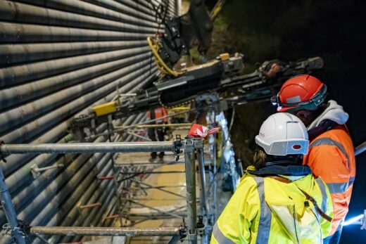 Deux ouvriers inspectent des machines sur un échafaudage.