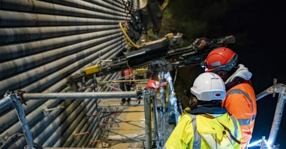 Deux ouvriers inspectent des machines sur un échafaudage.