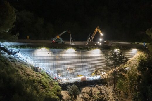 Ouvriers sur le pont VINCI illuminé, forêt environnante.