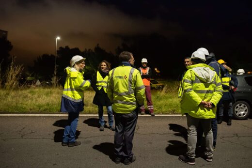 Groupe en gilets réfléchissants discutant sur route nocturne.