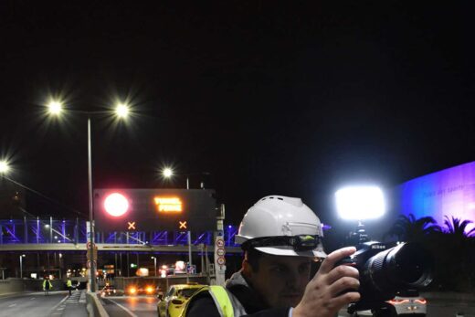 Personne en gilet jaune et casque VINCI filme la route.